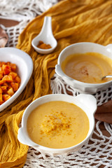 Pumpkin cream spiced with curry in a white bowl with roasted pumpkin and bread. Close Up