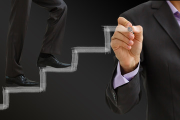 Businessman climbing the career stairs drawn on a chalkboard with copy space
