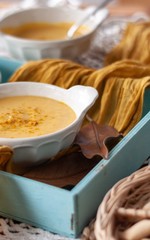 Pumpkin cream spiced with curry in a white bowl with roasted pumpkin and bread. Close Up