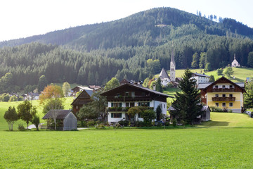 Fototapeta na wymiar Early morning in Austria. Traditional Austrian landscape: mountains, cozy houses and green lawns. Euro trip. Feeling of calm and stability.