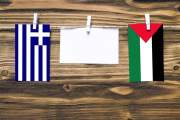 Hanging flags of Greece and Palestine attached to rope with clothes pins with copy space on white...