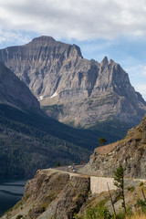 Beautiful View of Scenic Highway with American Rocky Mountain Landscape in the background during a Cloudy Summer Morning. Taken in Glacier National Park, Montana, United States.