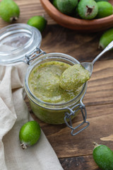 Fresh feijoa jam in a glass jar on the wooden background
