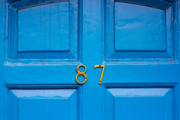 House number 87 on a bright blue wooden front door