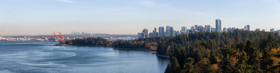 Fototapeta premium Downtown Vancouver, British Columbia, Canada. Beautiful Aerial Panoramic View of Seawall in Stanley Park with Downtown City in Background during a sunny Autumn Evening.