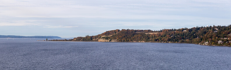 Fototapeta premium Beautiful Panoramic Aerial View of Discovery Park on the Ocean Shore during a cloudy autumn evening. Taken in Smith Cove Park, Seattle, Washington, United States.