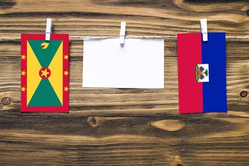 Hanging flags of Grenada and Haiti attached to rope with clothes pins with copy space on white note...