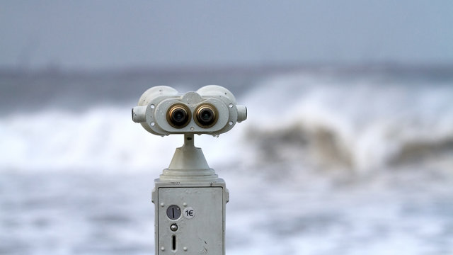Binocular de metal frente a un temporal de olas