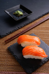 Salmon Nigiri Sushi on black slate stone with soy sauce and wasabi 