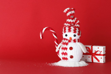 Creative snowman with gifts, sweet candy cane  on a red background with place for text.