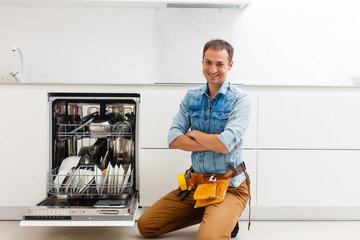 Plumber. smiling handsome plumber standing with crossed arms and looking at camera in kitchen