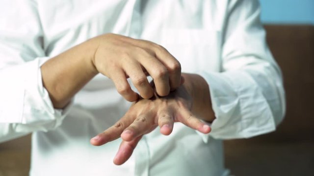 A man scratching his hand Because of itching