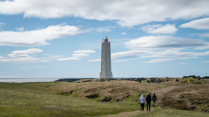 Fototapeta na wymiar Unidentified people walking towards Malarrif Lighthouse on the Snaefelssnes Peninsula in Iceland.