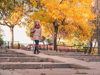 smiling young traveling girl with hat, scarf, boots and backpack, taking a walk on an autumn afternoon