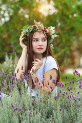 Beautiful long-haired girl in a wreath of flowers and berries. Portrait