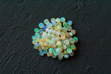 Opals gemstone from Ethiopia lies on black background. White fire opals with rainbowlike fire....
