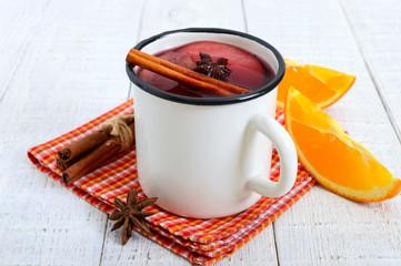 Hot mulled wine in a mug on a white wooden background. A traditional warming winter wine drink with aromatic spices.