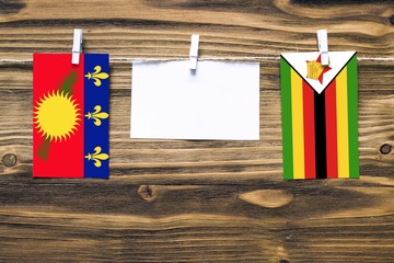 Hanging flags of Guadeloupe and Zimbabwe attached to rope with clothes pins with copy space on...