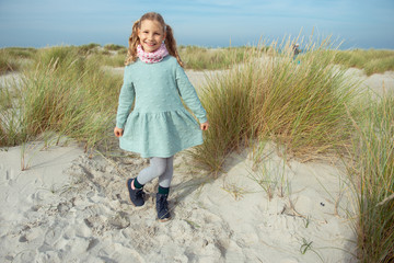 Portrait of pretty cheerful little girl in dress at sunny day on beach