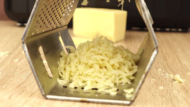 male hand rubs cheese on a metal grater