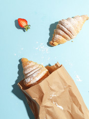 Appetizing croissants in a paper bag on a blue background. Top view.