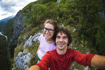 Couple taking a selfie against the backdrop of a mountain valley.