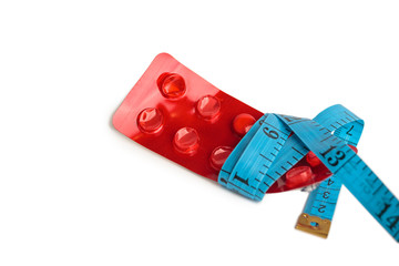 blister with tablets and tied with measuring tape, the concept of taking drugs for weight loss and maintain the figure, the harm of supplements for weight loss, isolated on white background