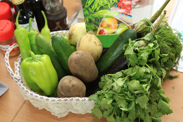 fresh vegetables . In the basket are peppers, cucumbers, onions, potatoes, greens, pickles, eggplant.