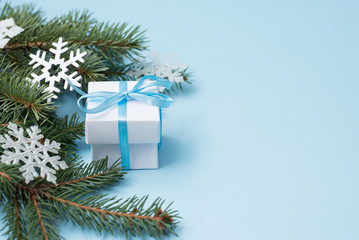 white christmas gift box on blue background,copy space. winter flat lay with green tree and snowflakes. greeting card