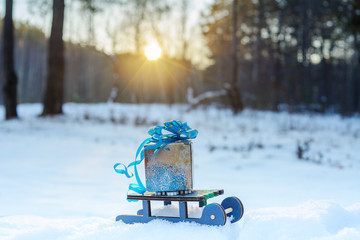 toy sleigh carrying a gift in the winter on this snow on a Sunny frosty day, winter mood, new year's card