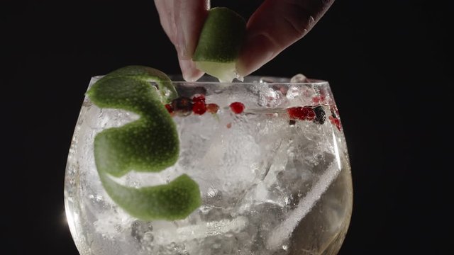 Close-up shot of making refreshing gin and tonic cocktail with lime against black background