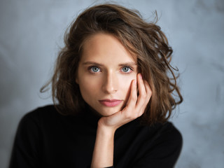 Closeup portrait of pensive girl with curly messy hair, she is thinking aboutsomething and touching...