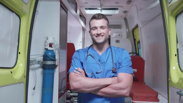 Man in medical uniform stand on the background of ambulance car.