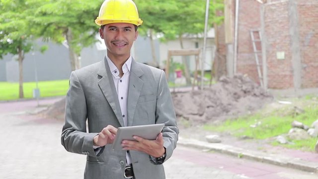male building designers or architech wearing helmets with tablet pc in front of unfinished brick house