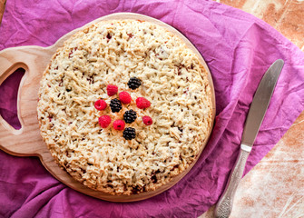 Homemade berry shortcrust pie with crumble on wooden board