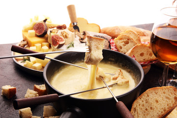 Gourmet Swiss fondue dinner on a winter evening with assorted cheeses on a board alongside a heated...