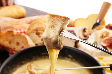 Gourmet Swiss fondue dinner on a winter evening with assorted cheeses on a board alongside a heated...
