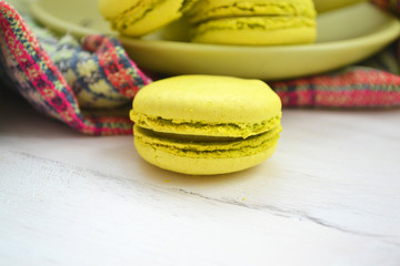 Macro image of a green macaron on a white shabby surface.