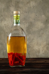 Acute, burning, red pepper infused with alcohol in a transparent bottle, is used for medicinal purposes, for warming up. Copy space, vertical arrangement.