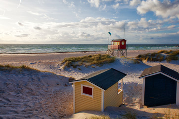 skanörs beach with colorful huts and red liveguard house at sunny cloudy evening sky © mschauer