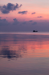 Tranquil seascape at dawn with pink sky and distant fishing boat, Koh Rong island, Cambodia