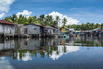 Fototapeta na wymiar Riverside houses in the unspoilt traditional fishing village of Prek Svay, Koh Rong island, Cambodia, south east Asia, on a calm sunny day.