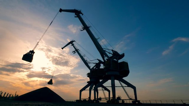 Industrial loaders are discharging gravel at sunset