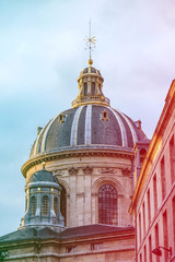 Fototapeta premium Blue dome under golden sunset light in Paris, France. Golden details glow under the golden light. Colored light leaks on the side.