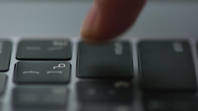 Man works in an office on a laptop, types text on a keyboard side view
