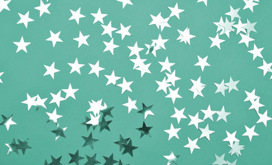 Festive background. Colorful glitter stars on mint color background.