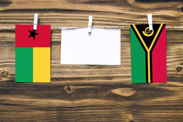 Hanging flags of Guinea Bissau and Vanuatu attached to rope with clothes pins with copy space on...
