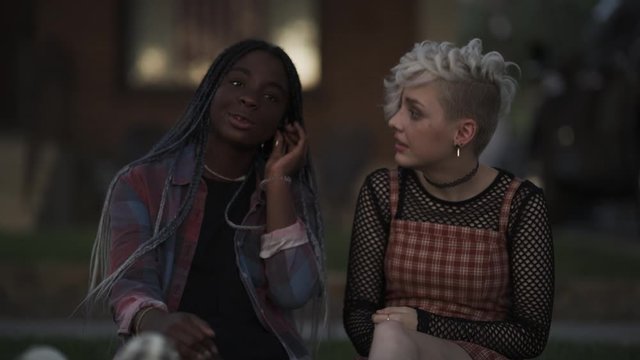 Girl sharing music with friend using wireless ear buds / Provo, Utah, United States