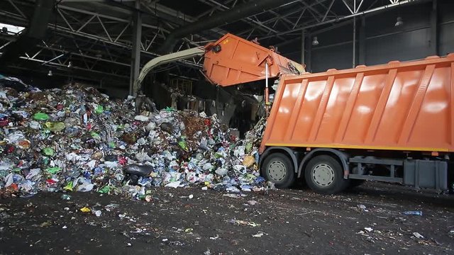 excavator stacks trash in big pile at sorting modern waste recycling processing plant. Separate and sorting garbage collection. Recycling and storage of waste
