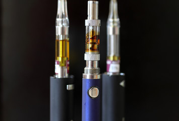 Vape pens and cartridges with a dark background.